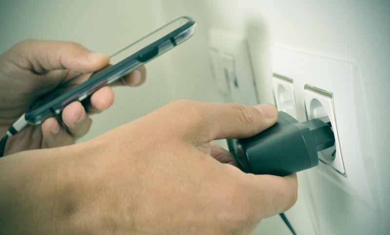 stock-photo-closeup-of-the-hands-of-a-man-plugging-in-the-plug-of-his-smpartphone-in-a-socket-with-a-filter